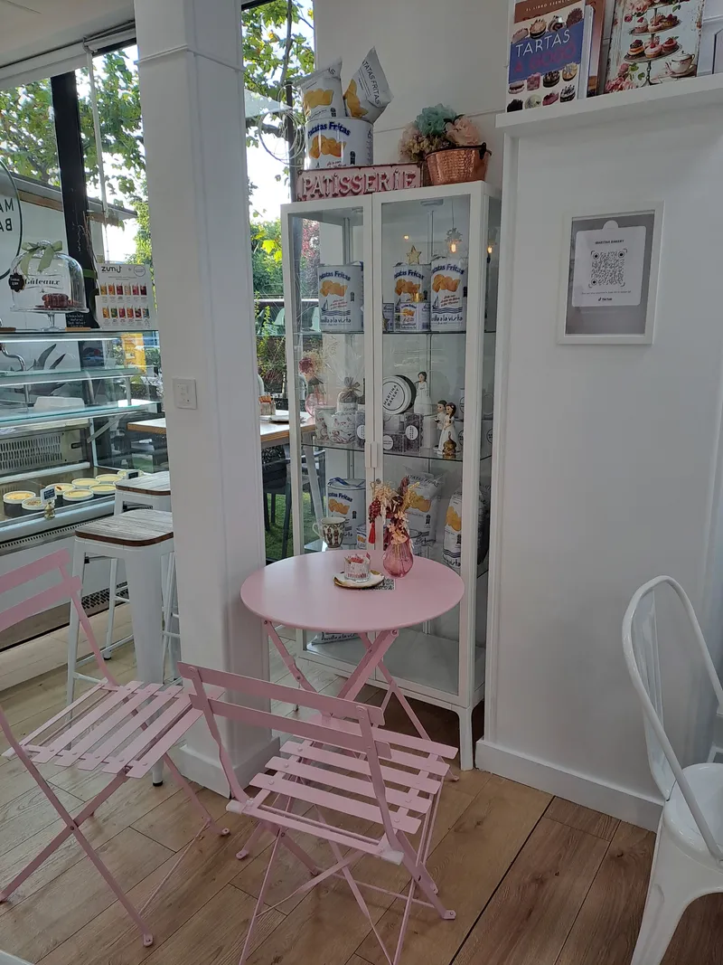 Rincón del local con mesa y vitrina de la pastelería